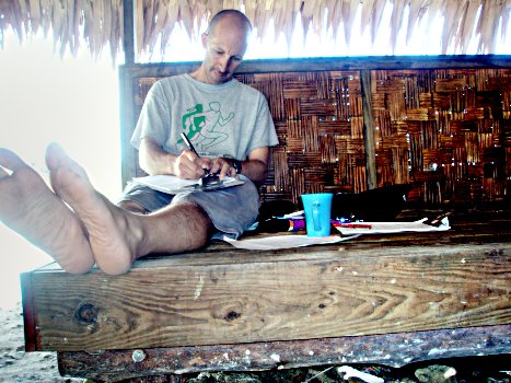 Prof marking papers. Huts provide a cool shade in which to do the marking.